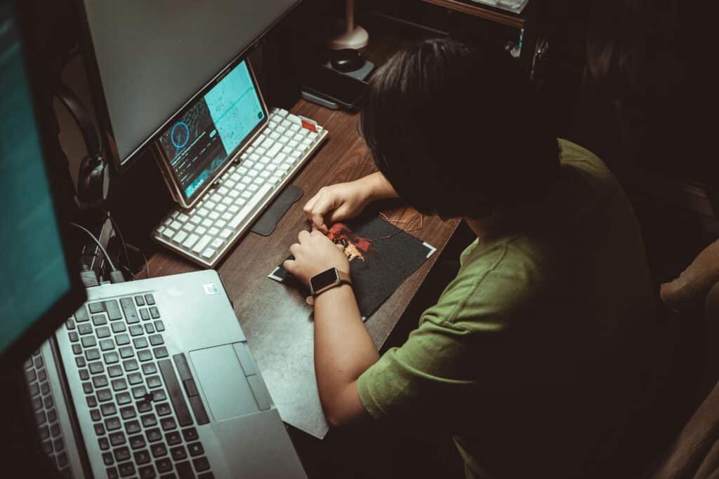 Person developing new skills at a desk, working on a creative project beside a laptop in a focused home workspace.